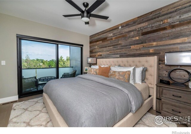 bedroom with wood walls, ceiling fan, and access to exterior