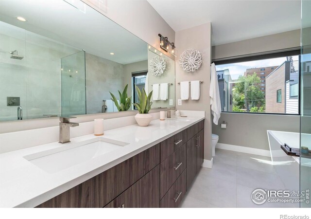 full bathroom featuring tile patterned floors, independent shower and bath, double sink vanity, and toilet