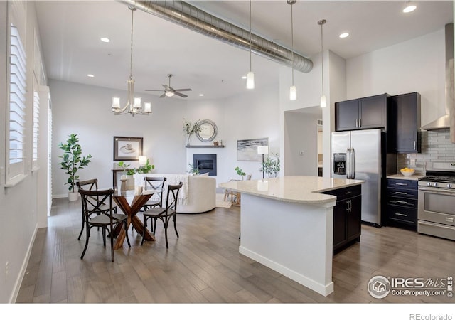 kitchen with a kitchen island, light wood-style flooring, stainless steel appliances, a glass covered fireplace, and tasteful backsplash