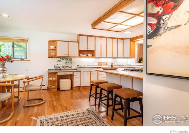 kitchen featuring open shelves, tasteful backsplash, recessed lighting, light wood-style floors, and a kitchen breakfast bar