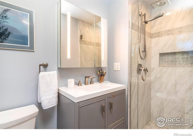 bathroom with toilet, a stall shower, and vanity