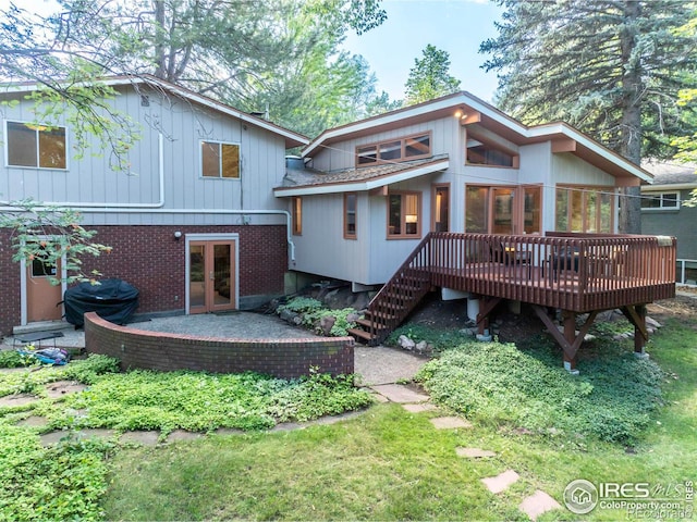 rear view of house with french doors, brick siding, a patio, and a wooden deck