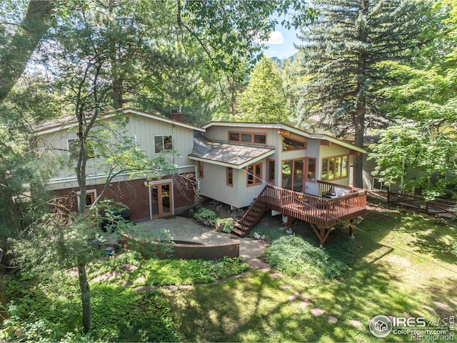 rear view of property featuring french doors, a yard, a chimney, a wooden deck, and stairs