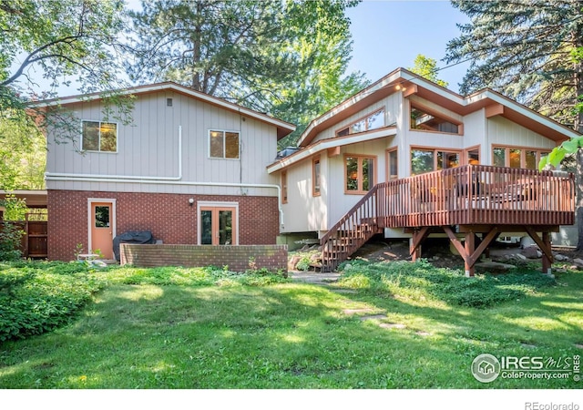 rear view of house featuring stairway, brick siding, a lawn, and a deck