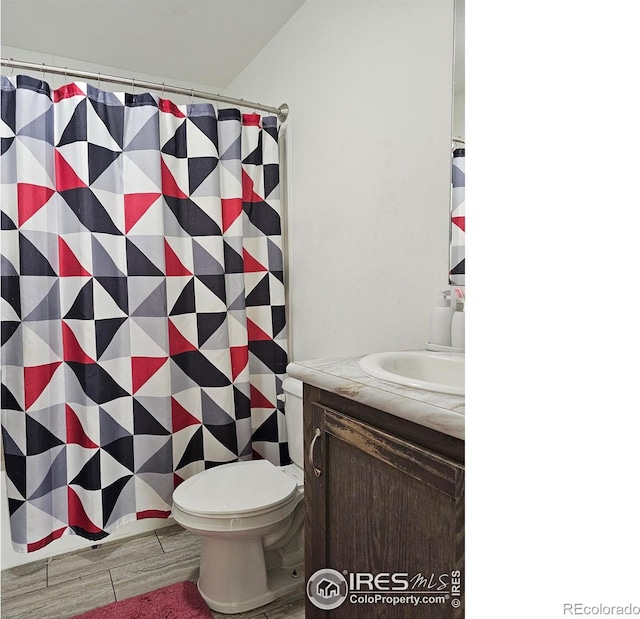 bathroom with a shower with shower curtain, hardwood / wood-style flooring, vanity, and toilet