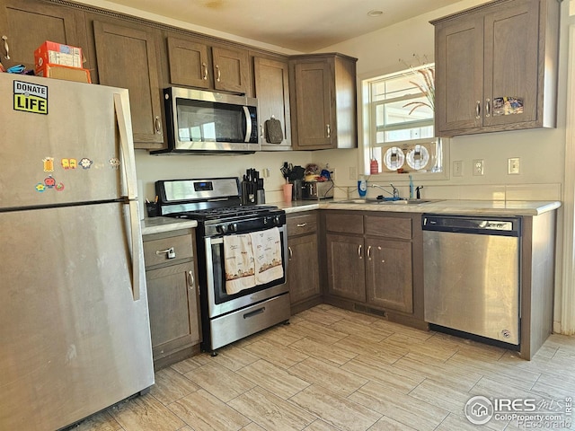 kitchen with appliances with stainless steel finishes, dark brown cabinetry, and sink