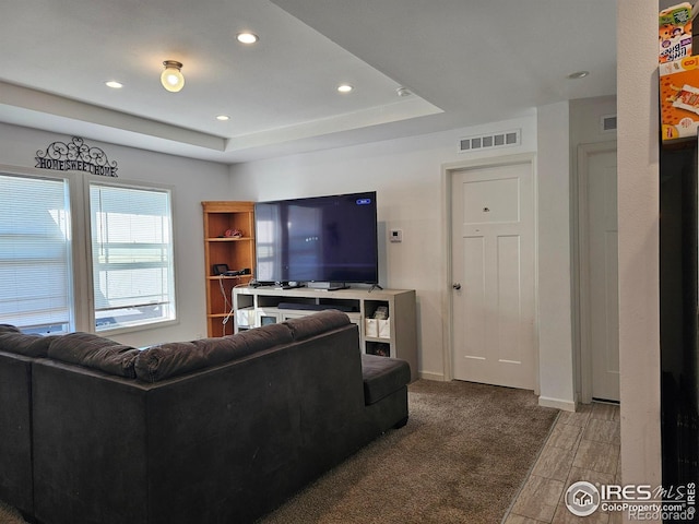 carpeted living room with a tray ceiling