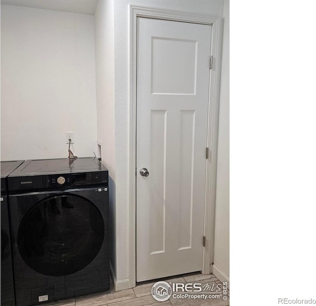 clothes washing area featuring light wood-type flooring and washer / clothes dryer