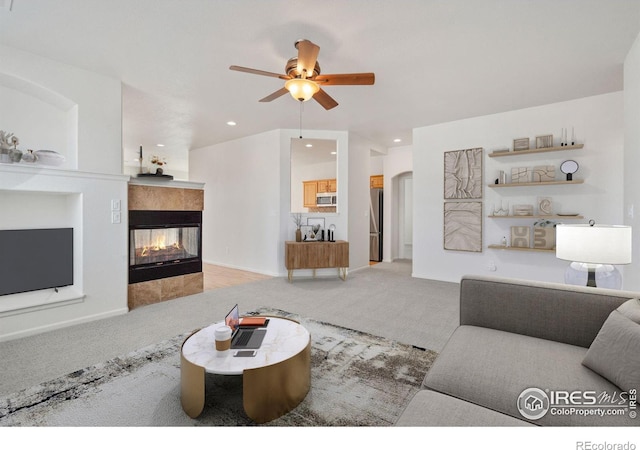 living room featuring carpet floors, ceiling fan, built in features, and a tile fireplace