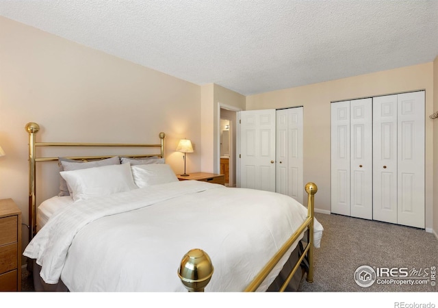 bedroom featuring multiple closets, carpet flooring, and a textured ceiling