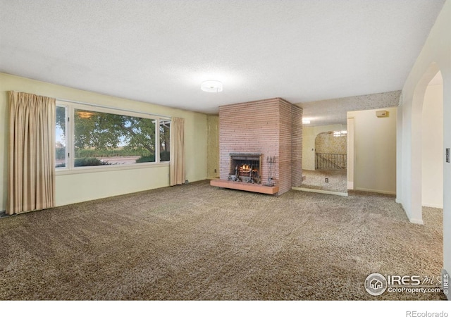 unfurnished living room with a fireplace, a textured ceiling, and carpet flooring