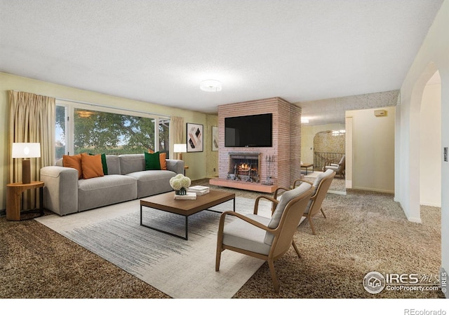 carpeted living room with a brick fireplace and a textured ceiling