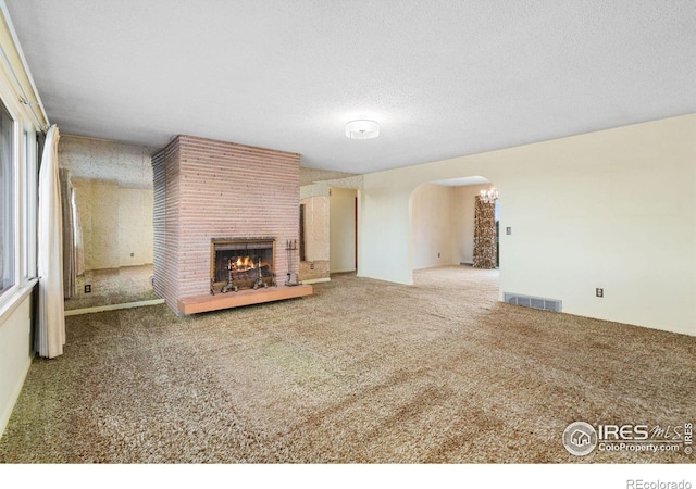 unfurnished living room with carpet, a textured ceiling, and a fireplace