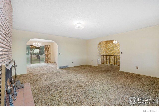 unfurnished living room with light carpet and a brick fireplace