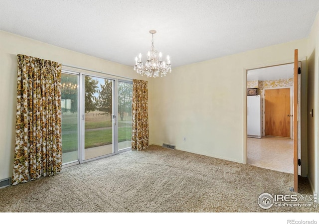 empty room with a textured ceiling, carpet flooring, and an inviting chandelier