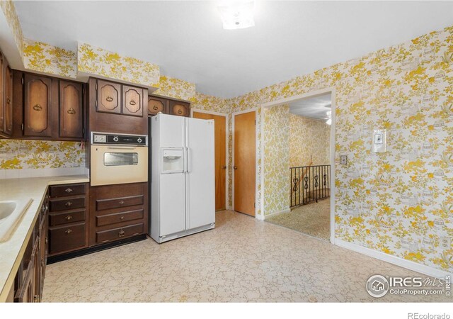 kitchen with dark brown cabinetry, white appliances, and sink