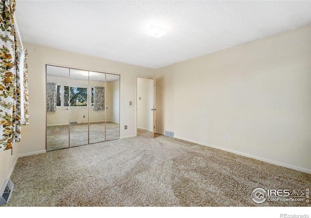 unfurnished bedroom featuring a closet, carpet, and a textured ceiling