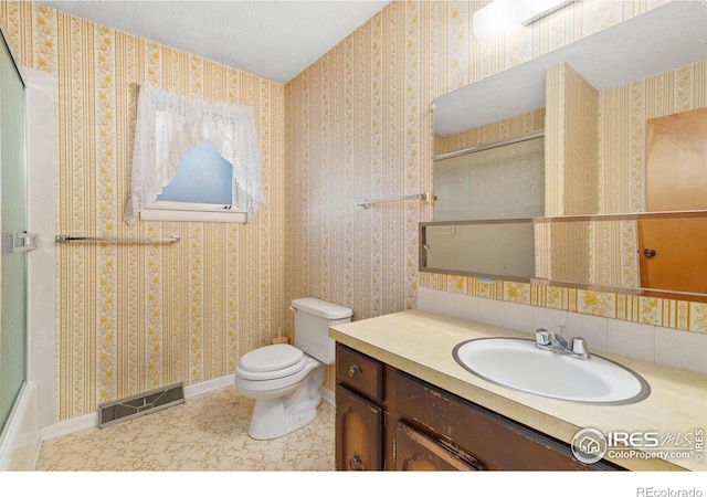 bathroom featuring toilet, vanity, a textured ceiling, and tile patterned floors