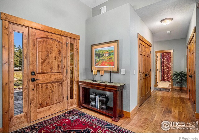 entryway with light wood-style flooring, baseboards, and a textured ceiling