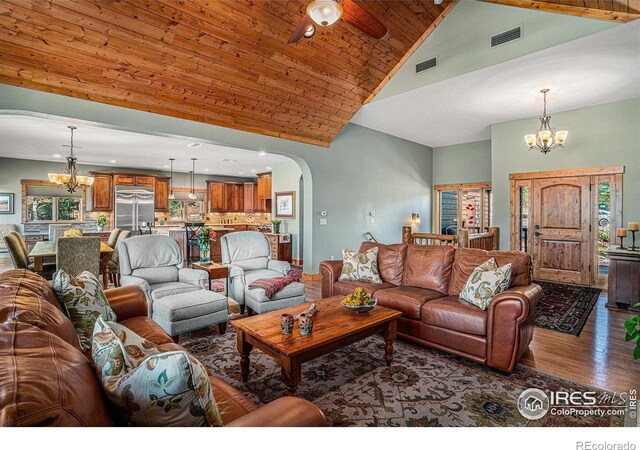 living room with hardwood / wood-style floors, ceiling fan with notable chandelier, high vaulted ceiling, and wooden ceiling