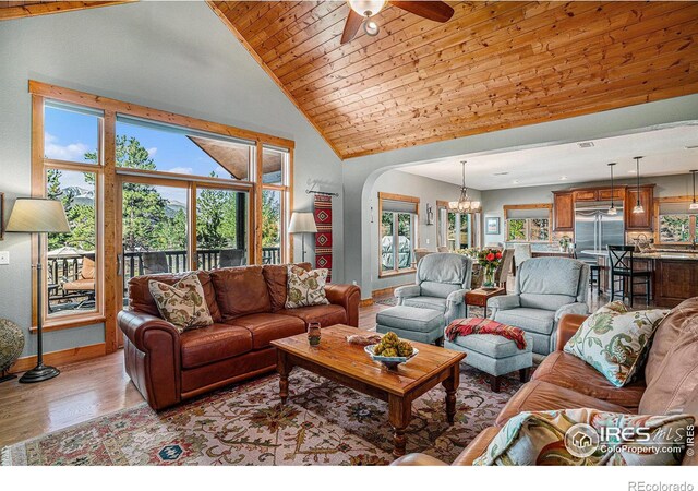 living room with light hardwood / wood-style floors, wood ceiling, high vaulted ceiling, and ceiling fan with notable chandelier