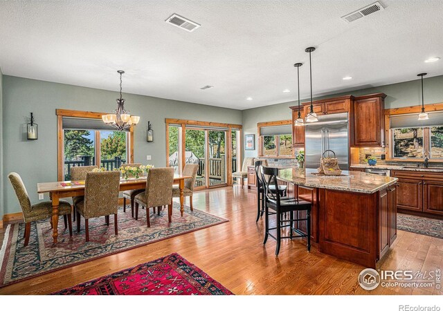 dining space with a chandelier, a textured ceiling, and light hardwood / wood-style floors