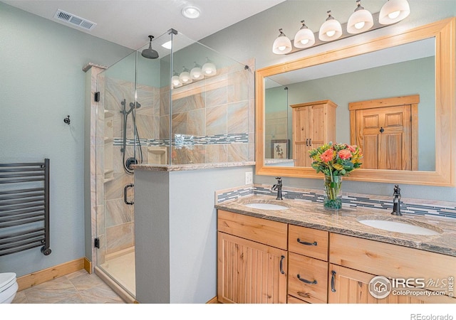 bathroom featuring a shower with door, vanity, radiator heating unit, and toilet