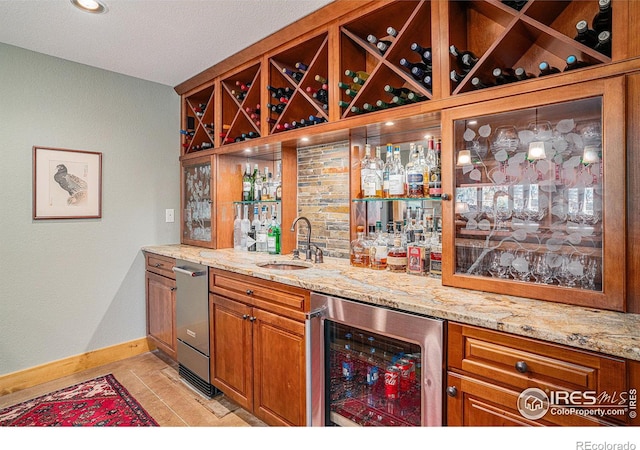 bar with light stone counters, sink, light tile patterned floors, and beverage cooler