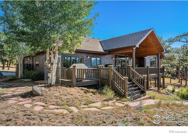 view of front of property with roof with shingles, stairs, and a wooden deck