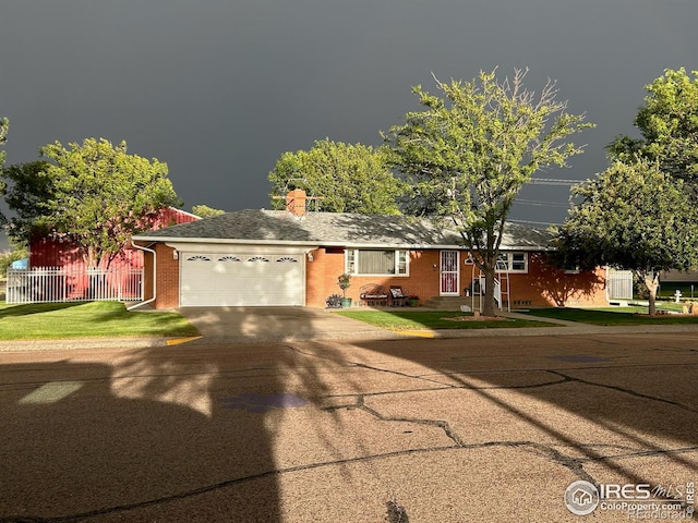 single story home with concrete driveway, a chimney, an attached garage, fence, and brick siding