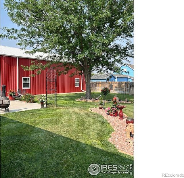 view of yard with a pole building, a patio, an outdoor structure, and fence