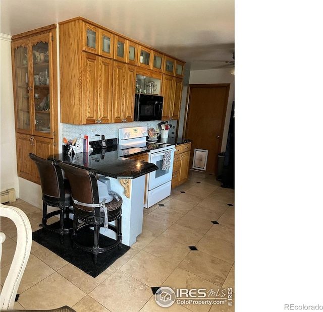 kitchen featuring brown cabinetry, black microwave, electric range, and a kitchen breakfast bar