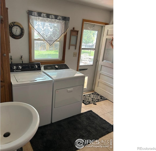 clothes washing area with laundry area, light tile patterned flooring, a sink, and independent washer and dryer