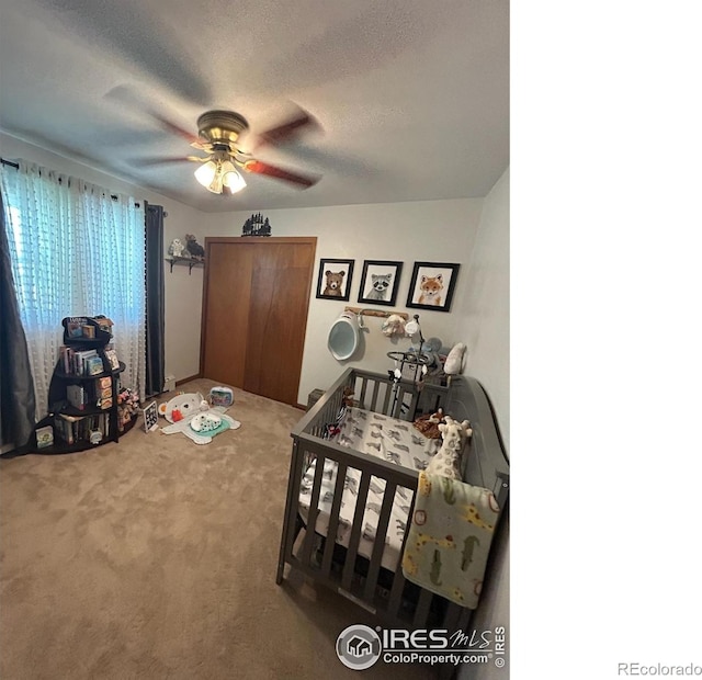 bedroom featuring a textured ceiling, ceiling fan, carpet floors, a closet, and a nursery area