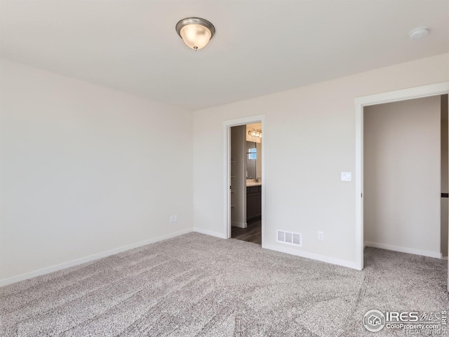 unfurnished bedroom featuring ensuite bath and carpet flooring