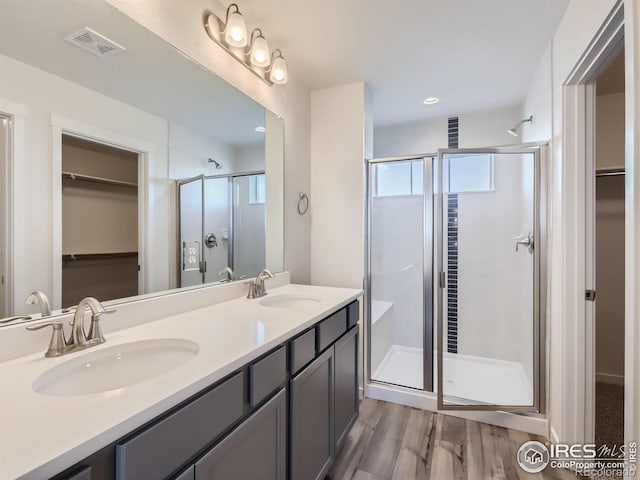 bathroom featuring hardwood / wood-style floors, a shower with door, and vanity