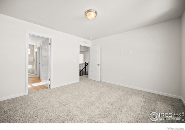 unfurnished bedroom featuring connected bathroom and light colored carpet