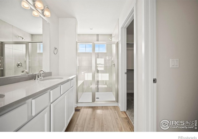 bathroom featuring walk in shower, vanity, and hardwood / wood-style flooring