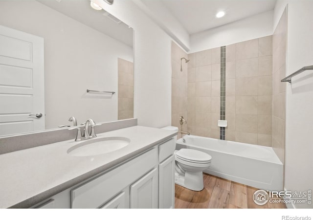 full bathroom featuring tiled shower / bath, vanity, toilet, and hardwood / wood-style floors