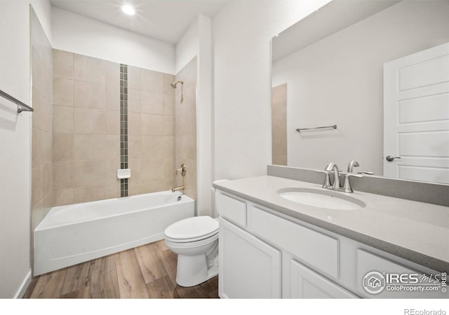 full bathroom with tiled shower / bath, wood-type flooring, toilet, and vanity