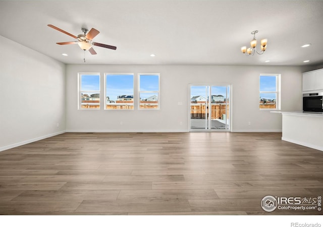 unfurnished living room featuring hardwood / wood-style flooring and ceiling fan with notable chandelier