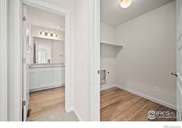 laundry room with hookup for an electric dryer, sink, and light hardwood / wood-style flooring