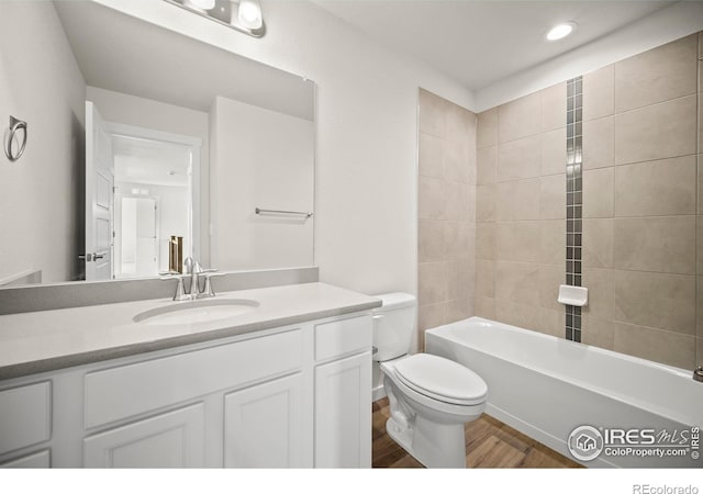 full bathroom with vanity, tiled shower / bath, hardwood / wood-style flooring, and toilet