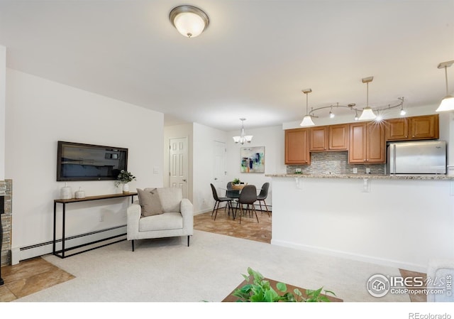 kitchen with pendant lighting, a baseboard radiator, stainless steel fridge, decorative backsplash, and light carpet