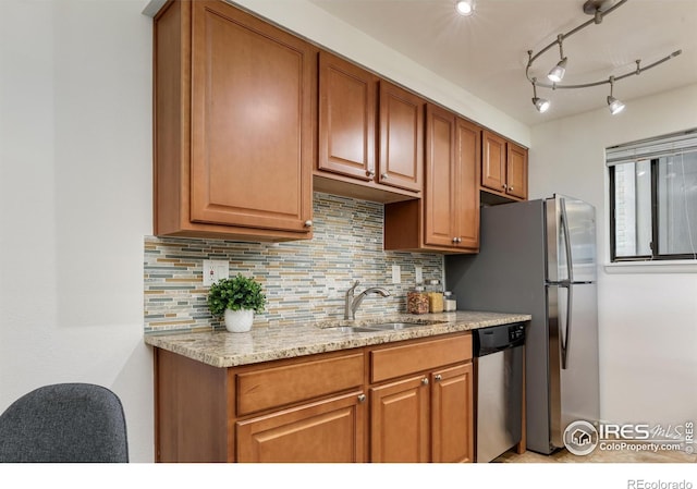 kitchen with stainless steel dishwasher, light stone countertops, sink, and backsplash