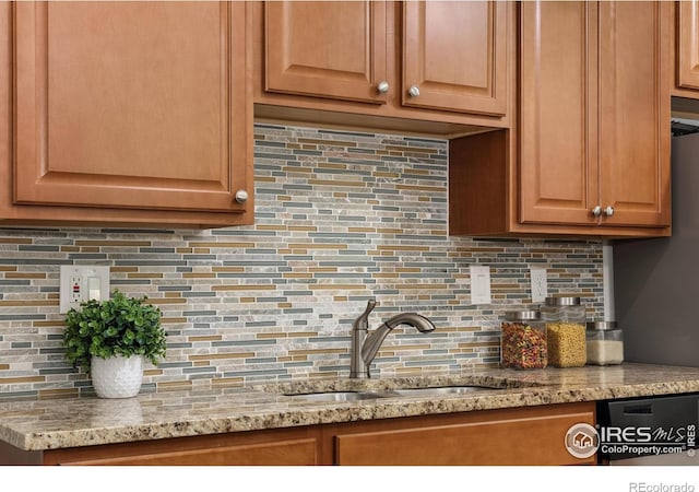 kitchen with tasteful backsplash, light stone countertops, and a sink