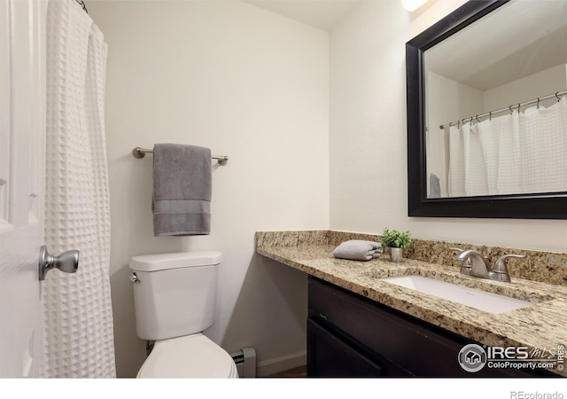 bathroom with a baseboard heating unit, baseboards, toilet, and vanity