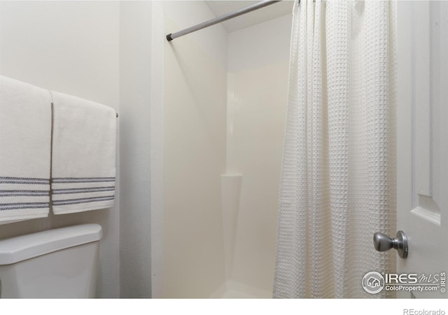 bathroom featuring curtained shower and toilet