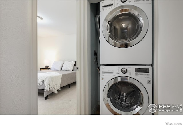 laundry room featuring a textured wall, laundry area, carpet, and stacked washer and dryer