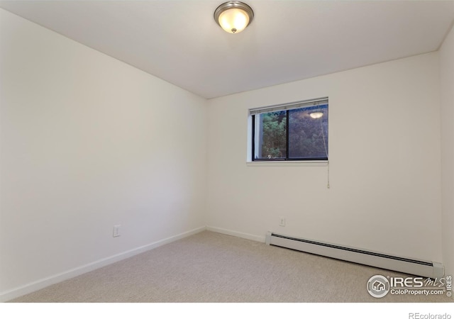 carpeted spare room with a baseboard radiator and baseboards